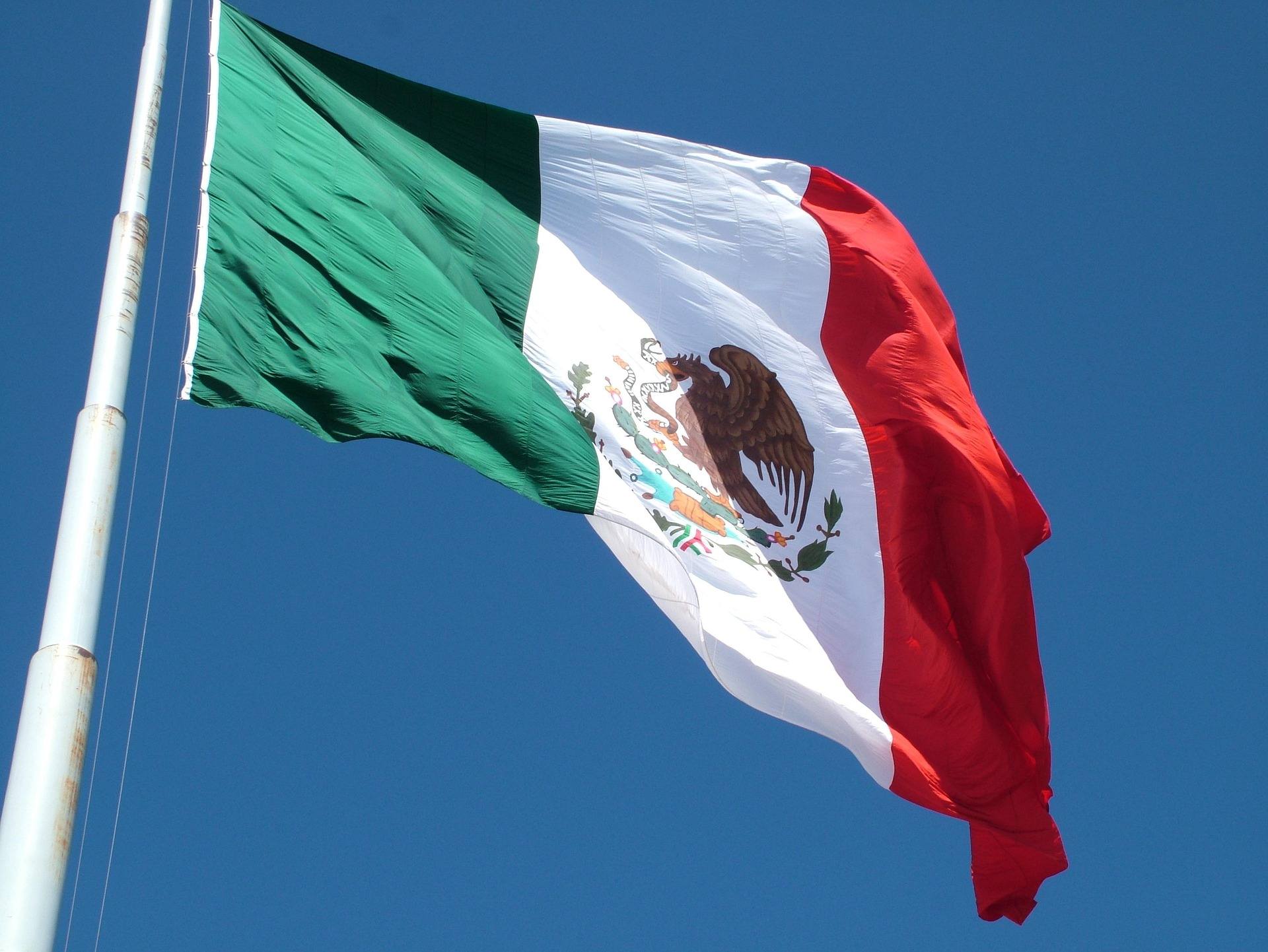 Mexikanische Flagge weht vor blauem Himmel – Symbolbild für das Auswandern nach Mexiko